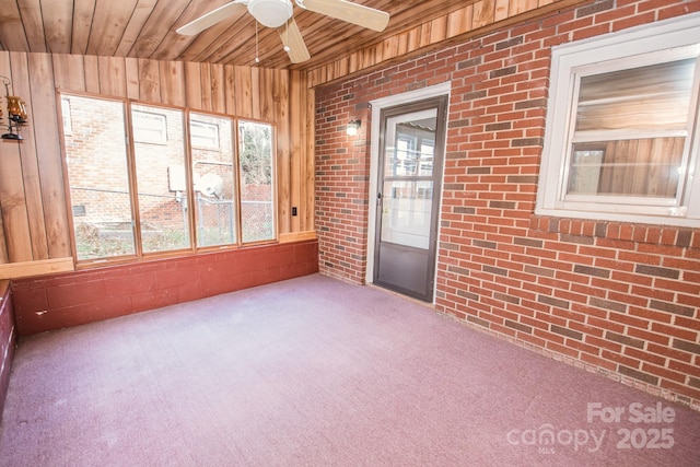 unfurnished sunroom with a healthy amount of sunlight, ceiling fan, and wooden ceiling