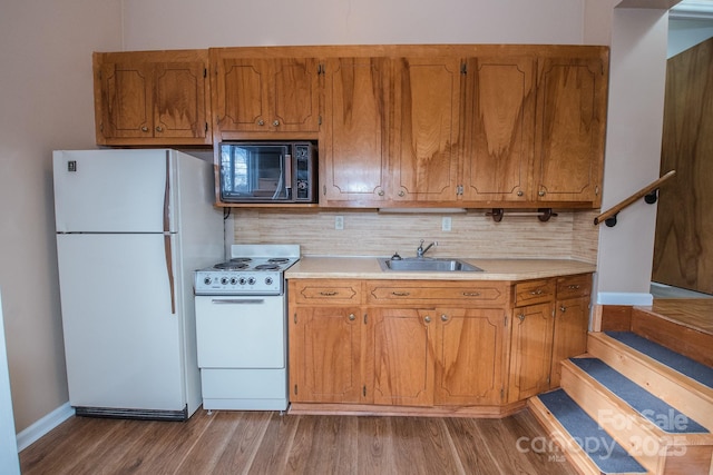 kitchen with tasteful backsplash, sink, hardwood / wood-style floors, and white appliances