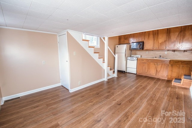 kitchen featuring hardwood / wood-style floors, white appliances, crown molding, sink, and decorative backsplash