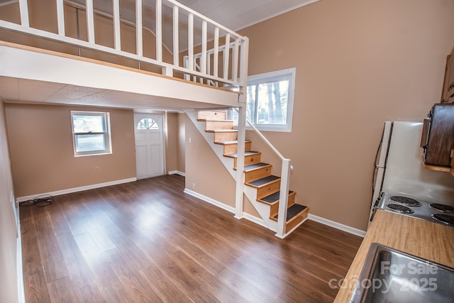 stairway with wood-type flooring and a towering ceiling