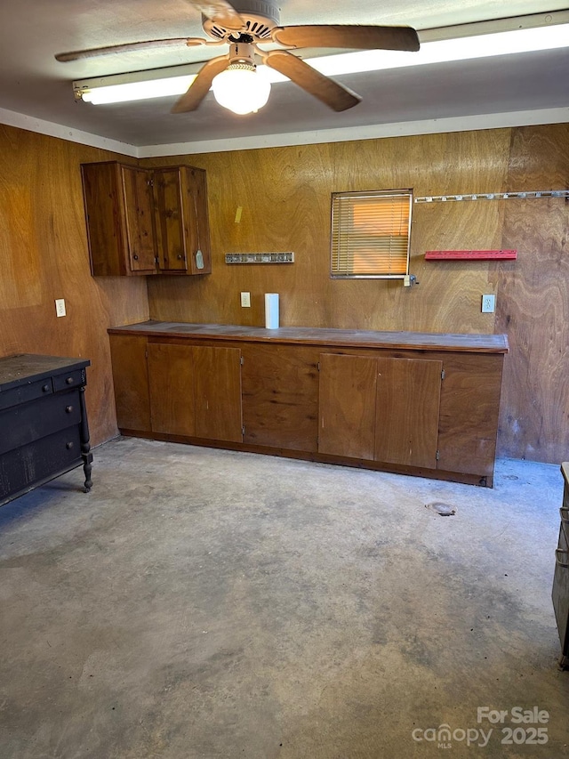 interior space featuring ceiling fan and wood walls