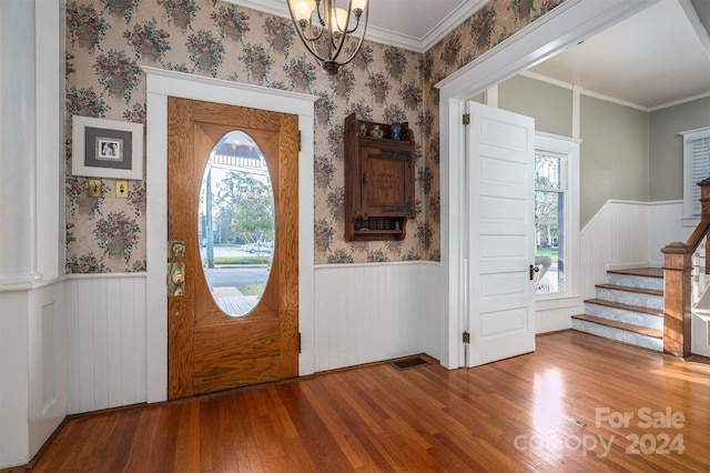 entrance foyer featuring hardwood / wood-style flooring, an inviting chandelier, and crown molding