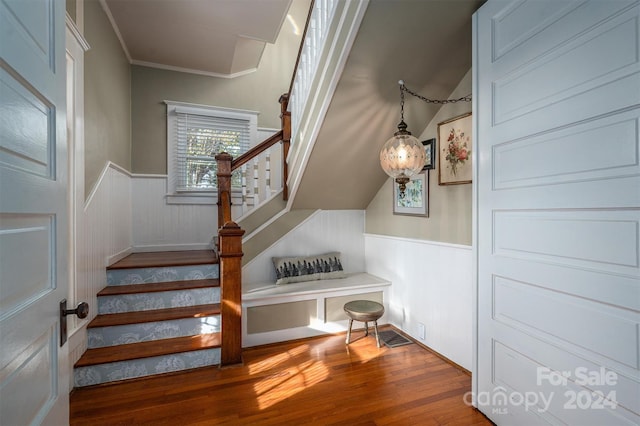 stairs with hardwood / wood-style floors and ornamental molding