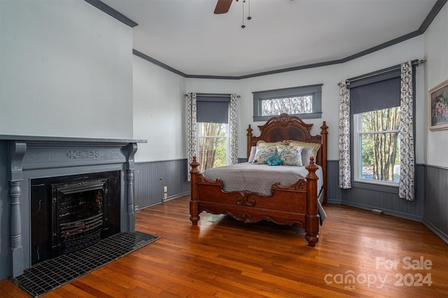 bedroom with ceiling fan, crown molding, wood-type flooring, and wood walls