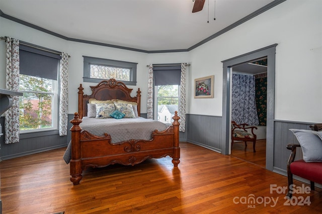 bedroom featuring hardwood / wood-style floors, ceiling fan, crown molding, and wood walls