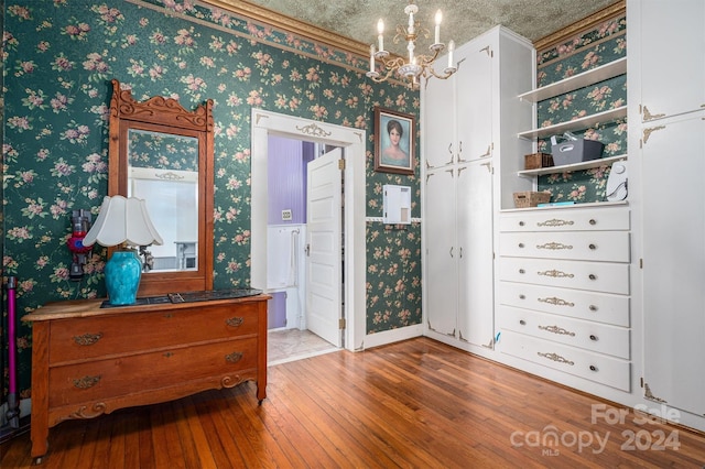 bedroom featuring crown molding, wood-type flooring, a textured ceiling, and a notable chandelier