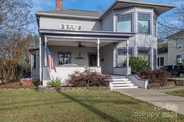 view of front of property with ceiling fan, covered porch, and a front lawn