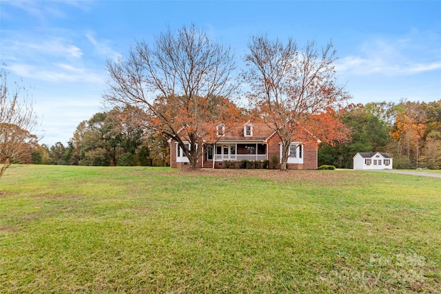 view of front of property with a porch, a front lawn, and an outdoor structure