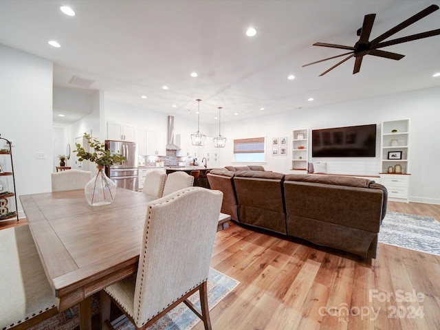 dining area featuring built in shelves, ceiling fan, sink, and light hardwood / wood-style floors