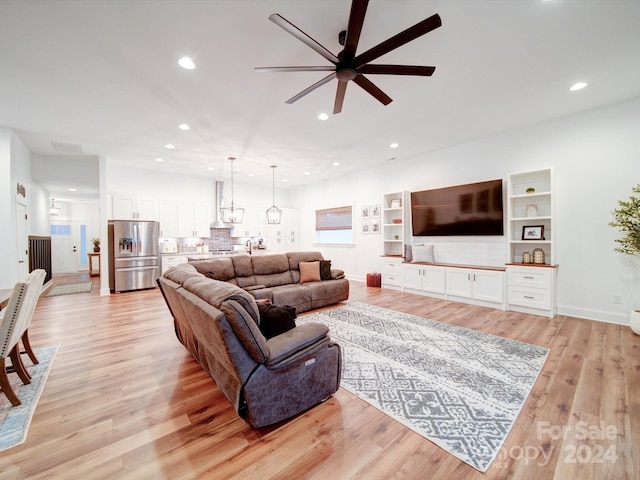 living room featuring light hardwood / wood-style flooring, ceiling fan, and sink