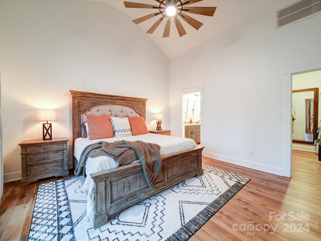 bedroom featuring ceiling fan, hardwood / wood-style floors, high vaulted ceiling, and ensuite bathroom