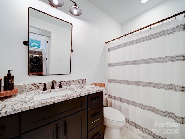 bathroom featuring washer / dryer, vanity, and toilet