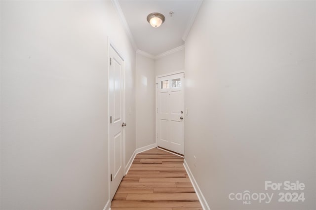 hall with ornamental molding and light wood-type flooring