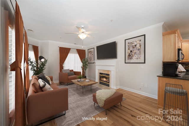 living room with light hardwood / wood-style floors, ceiling fan, and crown molding