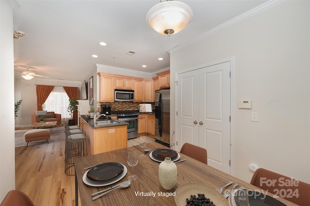 dining space with light wood-type flooring, ceiling fan, ornamental molding, and sink