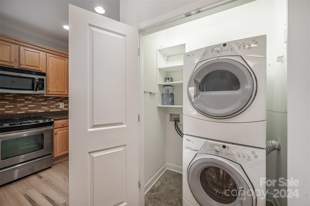 clothes washing area with stacked washer / dryer, hardwood / wood-style floors, and ornamental molding