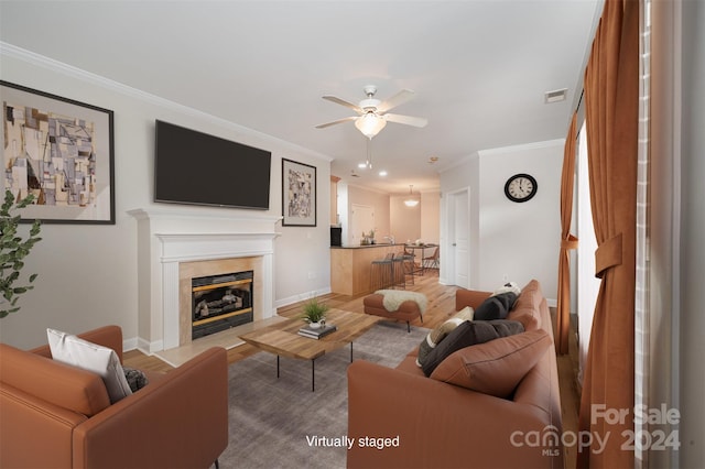 living room featuring wood-type flooring, ceiling fan, and ornamental molding