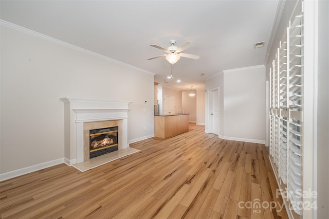 unfurnished living room featuring crown molding, ceiling fan, and light hardwood / wood-style floors