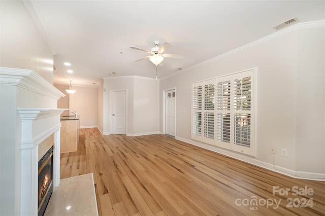 unfurnished living room featuring ceiling fan, light wood-type flooring, and crown molding