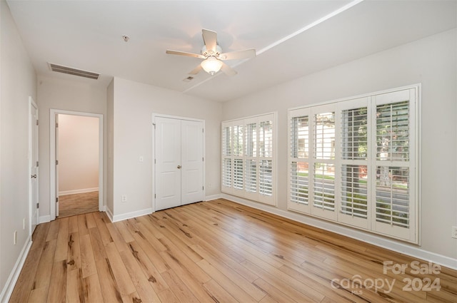 unfurnished bedroom featuring ceiling fan, light wood-type flooring, and a closet