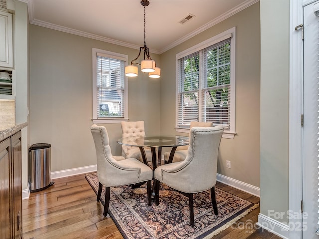 dining room featuring an inviting chandelier, ornamental molding, light wood-type flooring, and a wealth of natural light