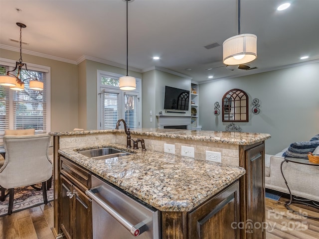 kitchen with a kitchen island with sink, sink, hanging light fixtures, and dishwasher