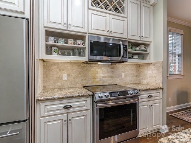 kitchen with white cabinetry, ornamental molding, appliances with stainless steel finishes, light stone countertops, and backsplash