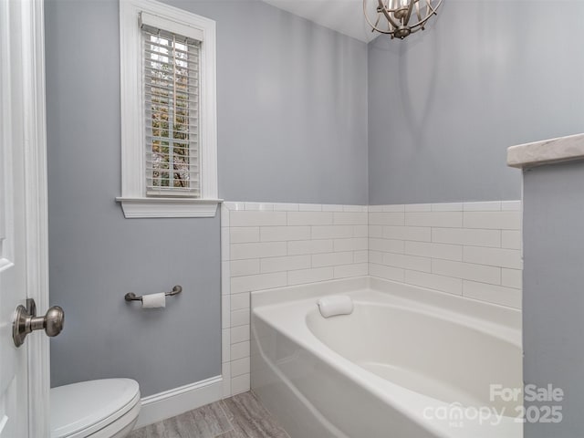 bathroom with a washtub, hardwood / wood-style floors, and toilet