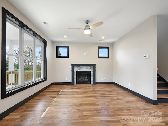 unfurnished living room featuring a fireplace, light wood-type flooring, and ceiling fan