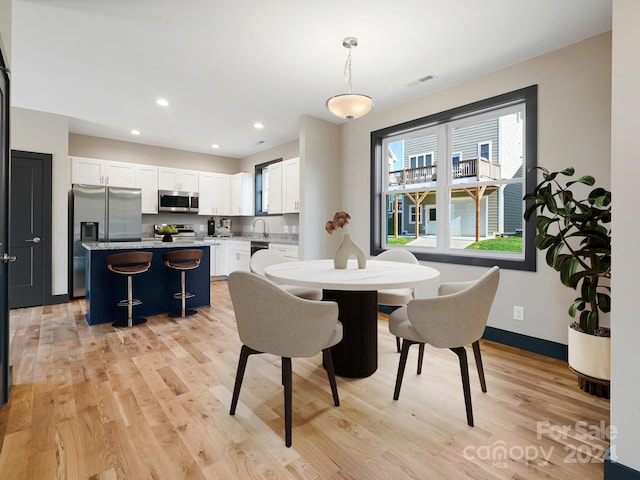 dining space with light hardwood / wood-style flooring and sink