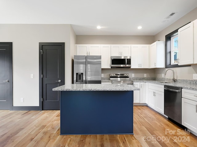 kitchen with light wood-type flooring, appliances with stainless steel finishes, a center island, and white cabinetry