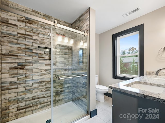 bathroom with toilet, vanity, tile patterned floors, and a shower with door