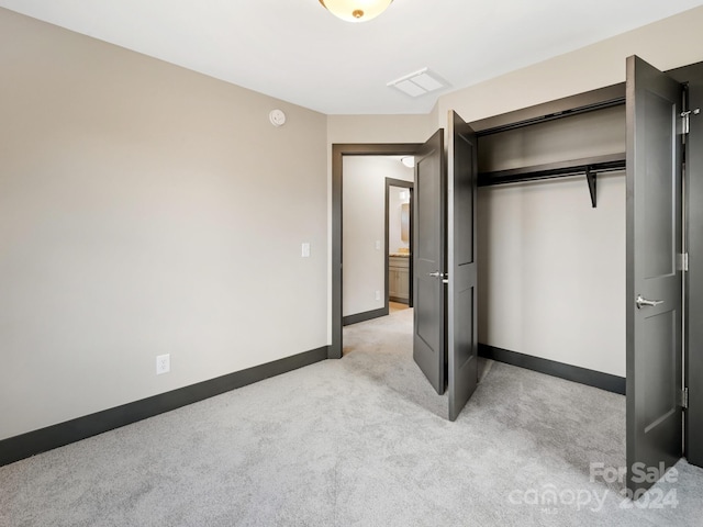 unfurnished bedroom with light carpet and a closet