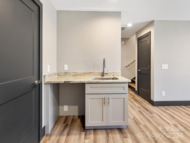 kitchen with light stone counters, sink, and light hardwood / wood-style flooring