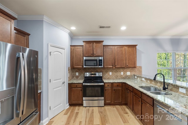 kitchen with light stone countertops, sink, stainless steel appliances, and light hardwood / wood-style floors