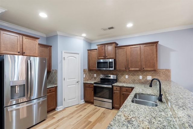 kitchen with crown molding, sink, light wood-type flooring, appliances with stainless steel finishes, and light stone counters