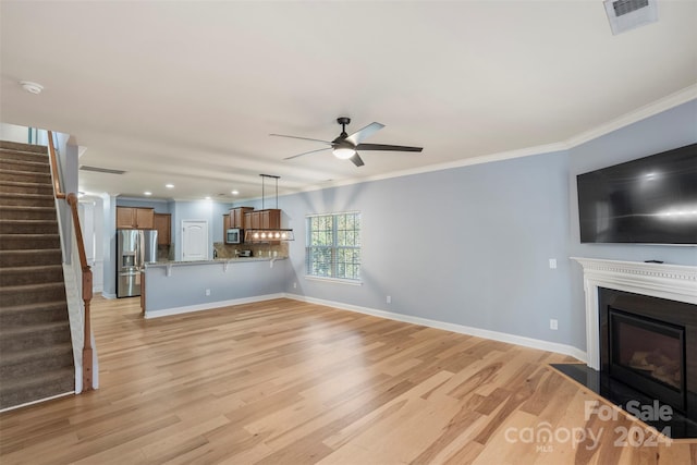 unfurnished living room with light wood-type flooring, ceiling fan, and crown molding