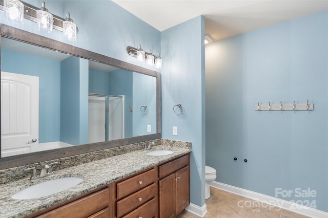 bathroom featuring tile patterned floors, vanity, toilet, and a shower with door