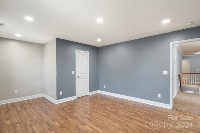 empty room with hardwood / wood-style floors, tile walls, and ornamental molding