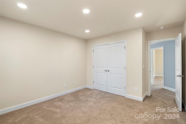 unfurnished bedroom featuring a closet and light colored carpet