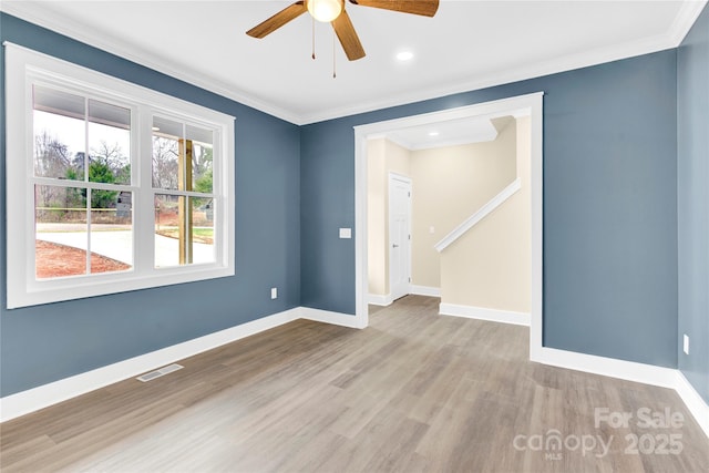 empty room featuring baseboards, crown molding, visible vents, and wood finished floors