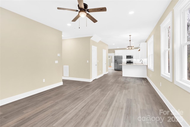 unfurnished living room featuring baseboards, wood finished floors, and recessed lighting