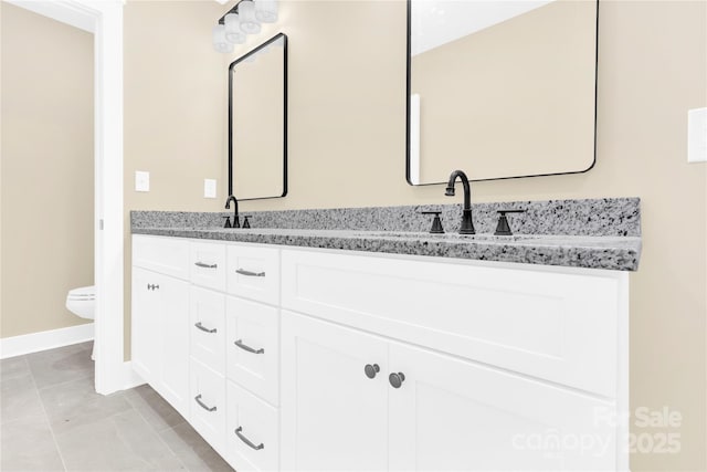 bathroom featuring toilet, tile patterned flooring, double vanity, and a sink