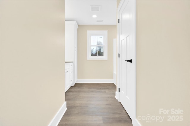 corridor with visible vents, baseboards, and wood finished floors