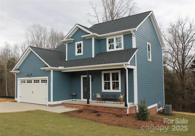 view of front facade featuring a porch, an attached garage, central AC, roof with shingles, and a front yard