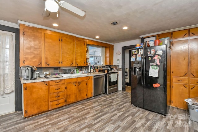 kitchen featuring appliances with stainless steel finishes, tasteful backsplash, ornamental molding, ceiling fan, and light hardwood / wood-style floors