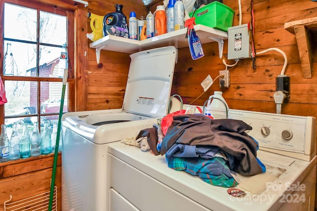 laundry room with wooden walls and washer and clothes dryer