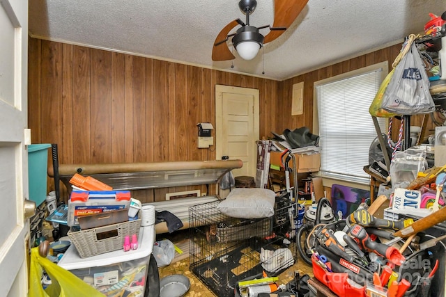 miscellaneous room with a textured ceiling, ceiling fan, and wooden walls