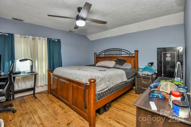 bedroom with lofted ceiling, ceiling fan, a textured ceiling, and light wood-type flooring