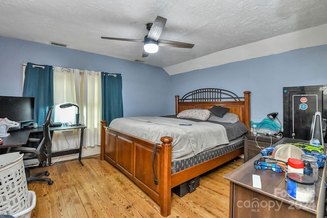 bedroom with vaulted ceiling, ceiling fan, light hardwood / wood-style floors, and a textured ceiling